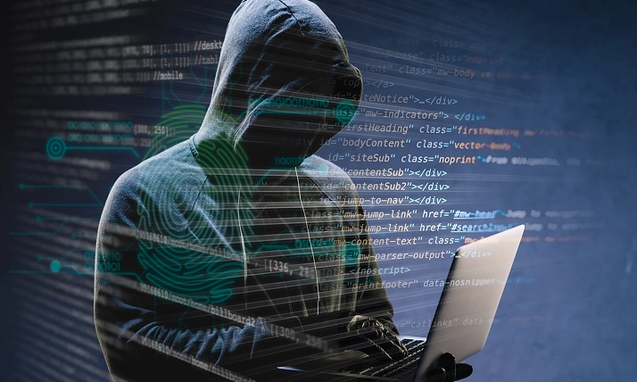 Hacker in hoodie using laptop, surrounded by digital code, representing cybersecurity threat concept.